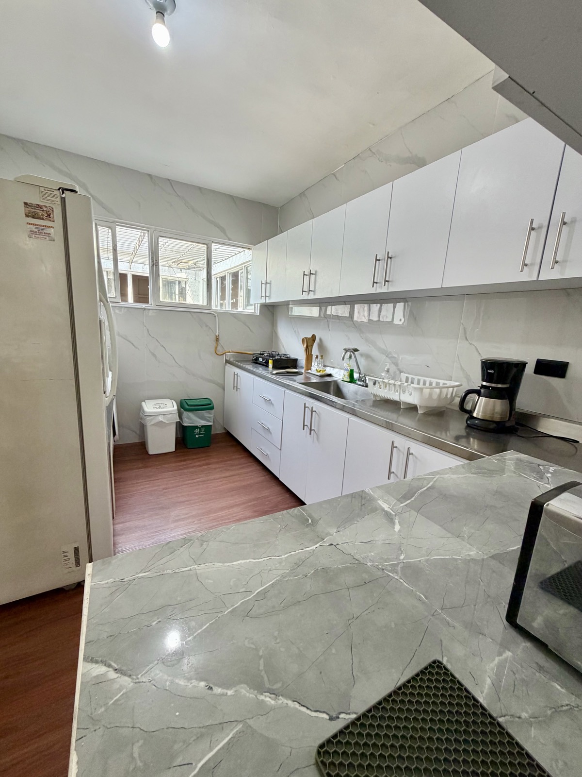 Cocina compartida del Hostal Beko con mesón de acero y ventanas